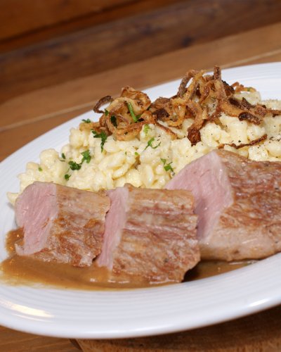 Herzhafte Kässpatzen aus der Riesenpfanne mit abgeschmolzenen Zwiebeln rosa gebratenes Schweinelendchen und Rahmsauce.