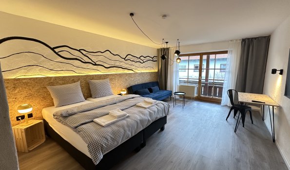 Modernes Zimmer mit Aussicht in einer Stadt In einem Zimmer befinden sich ein großes Bett, ein Sofa und ein Schreibtisch. Es gibt viel Licht und eine schöne Aussicht.