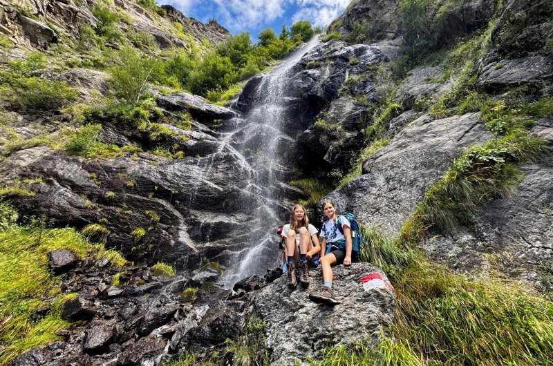 Wanderer sitzen neben einem Wasserfall im Gebirge