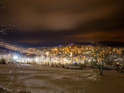 Die Stadt erstrahlt nachts in warmem Licht, während Schnee die Landschaft bedeckt und die Stille des Winters verleiht.