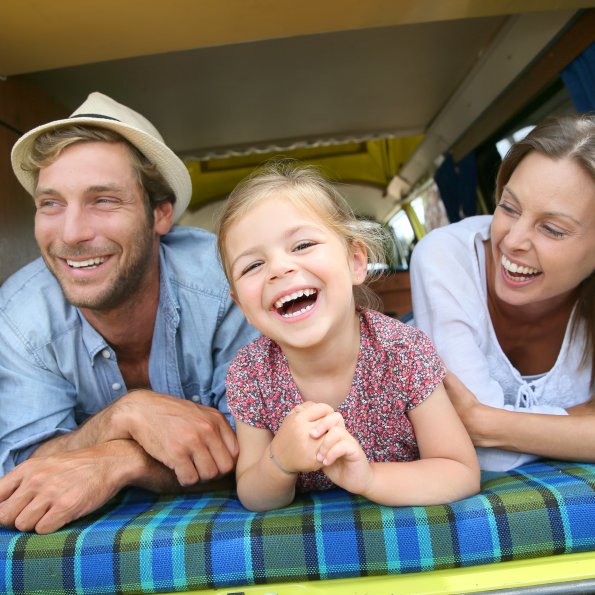 Familie Wohnmobil Wurzelrudi Eine Familie lacht und entspannt sich in einem Wohnmobil. Sie genießen die Zeit zusammen und haben Spaß.
