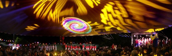 Lichtershow Schalmeientreffen Menschen stehen versammelt und schauen sich eine Lichtershow unter einem großen Zelt an. Musik spielt im Hintergrund.