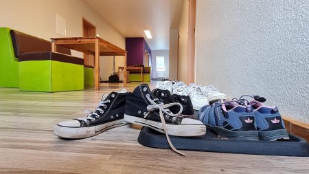 Schuhe stehen in einem Flur eines modernen Raums Verschiedene Schuhe stehen im Flur eines modernen Raums, in einer hellen Umgebung mit Holzboden und Fenstern.