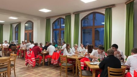 Die Mensa ist gut besucht. Menschen sitzen an Tischen, essen und unterhalten sich in geselliger Runde.