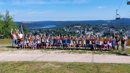 Eine Gruppe von Kindern steht zusammen auf einem Hügel. Sie lachen und haben die Hände in die Luft erhoben.
