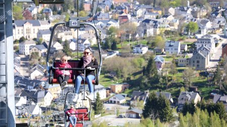 Zwei Personen sitzen in einer Seilbahn und genießen die Aussicht auf eine Stadt in den Bergen.